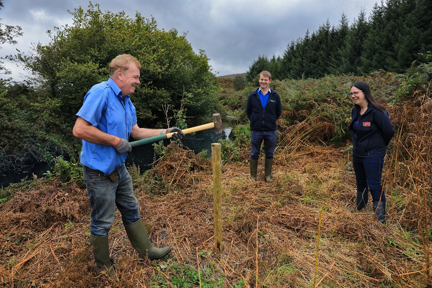 A farmer in the Caha catchment is fencing off his river, with the help of two Teagasc advisors who are looking on.