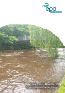 A swollen river with brown, fast-moving water flowing beneath a metal footbridge surrounded by lush green trees. The image includes the EPA logo at the top and text at the bottom reading “Hydrology Bulletin – November 2025: A monthly hydrological summary for Ireland.”
