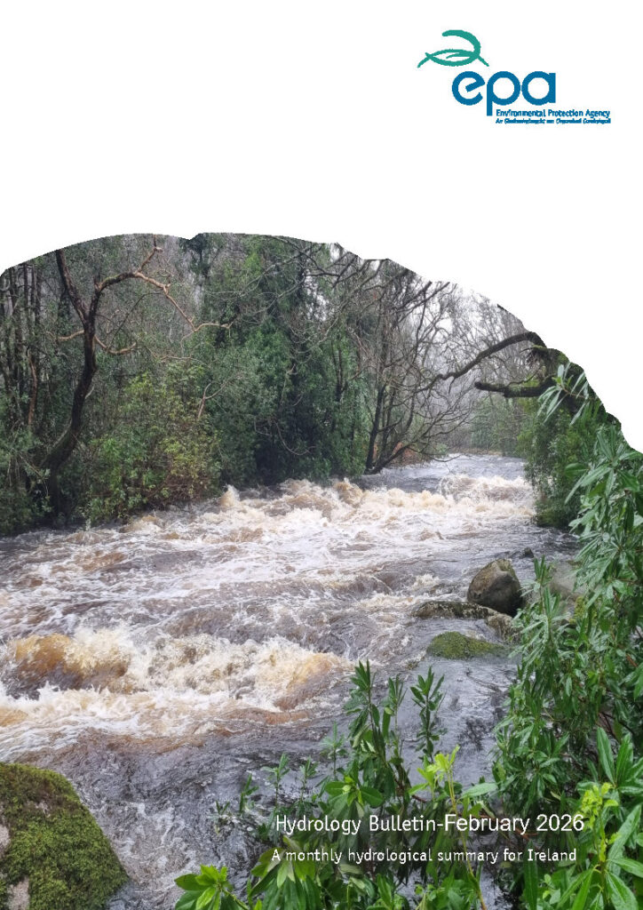 A fast‑flowing, swollen river moves through a forested area with dense trees and vegetation on both sides. The water is brown and turbulent, suggesting recent heavy rainfall or high flow conditions. Green shrubs and mossy rocks are visible in the foreground. At the top right, the Environmental Protection Agency (EPA) Ireland logo appears in blue and green. At the bottom right, white text reads “Hydrology Bulletin February 2026, A monthly hydrological summary for Ireland.”